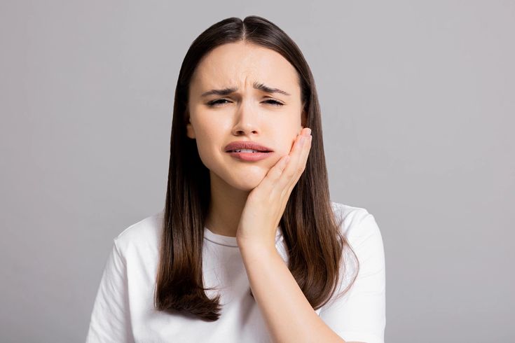 Femme ressentant une douleur liée à une sensibilité dentaire